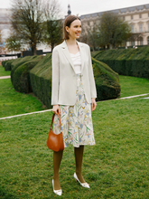 a lady wears a floral printed midi skirt with a light green blazer